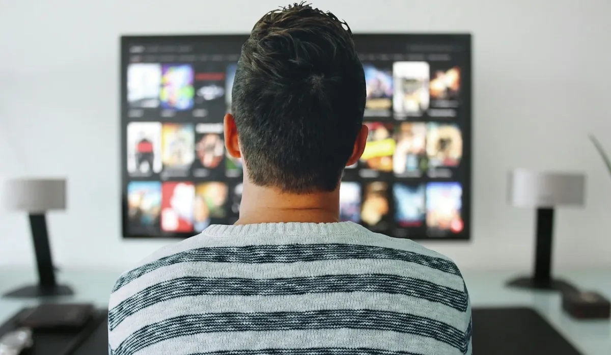 Mężczyzna oglądający telewizję w domowym zaciszu podczas świętowania Nowego Roku.